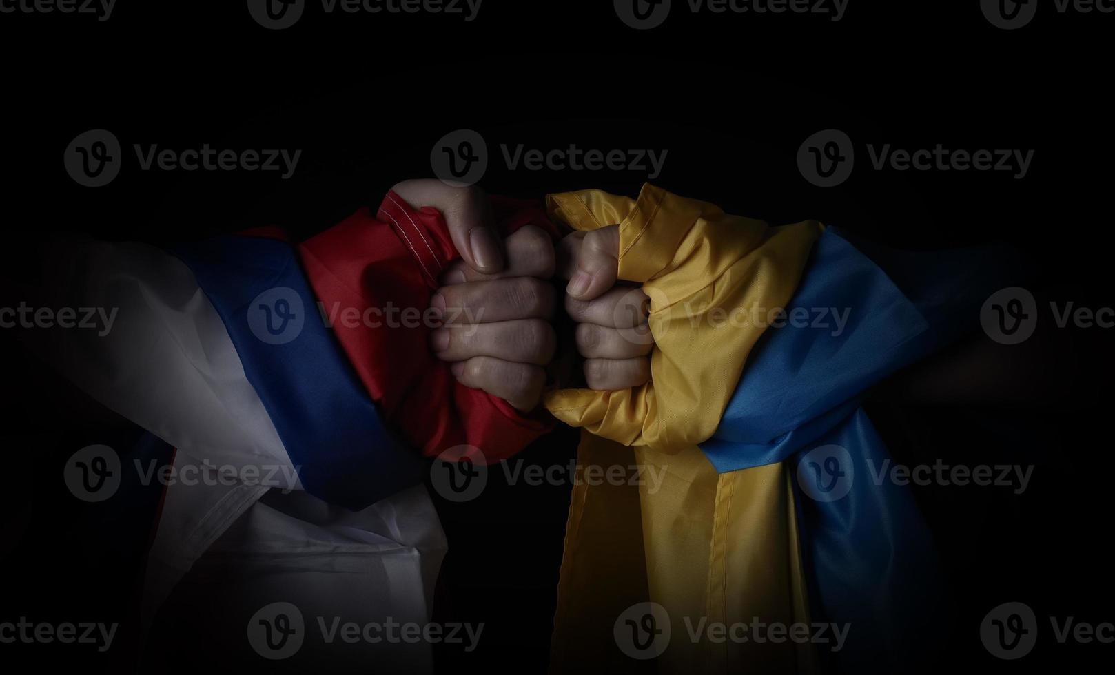 Russian flag and Ukraine flag in hands showing symbol of struggle war photo