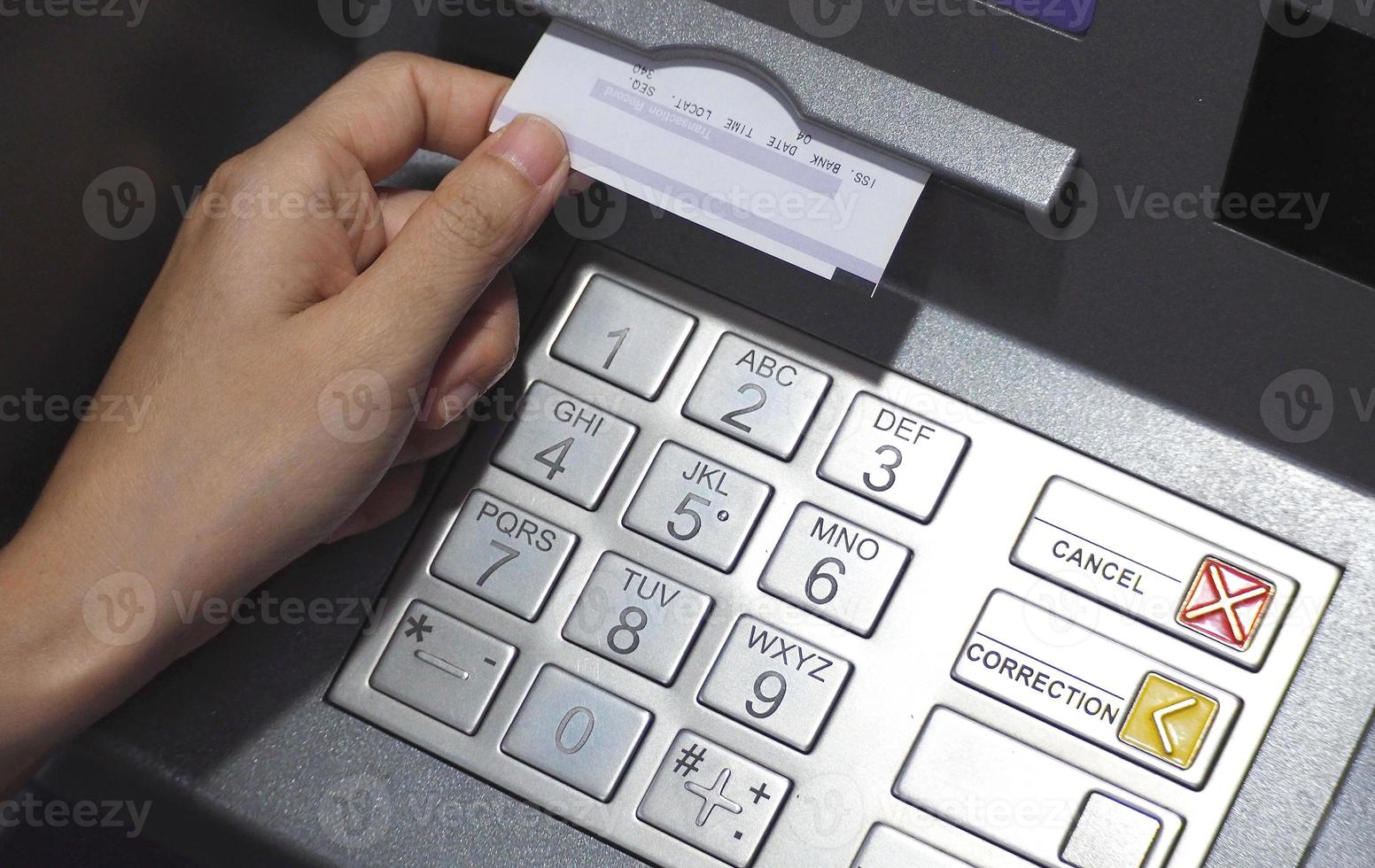ATM button close up and paper transaction deposit pay slip and hand. photo
