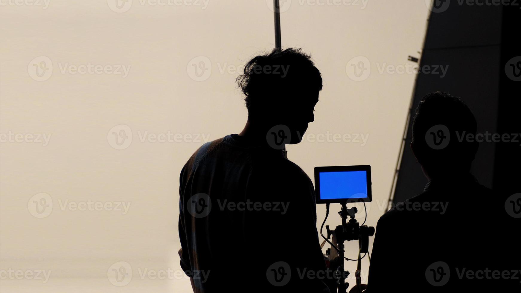 el director de cine y el fotógrafo están hablando o consultando para hacer un estudio antes de grabar video e iluminación de fondo de silueta. foto