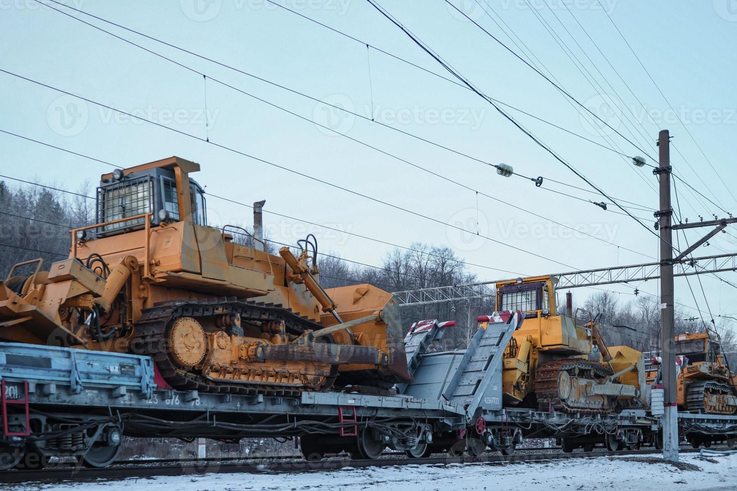 Heavy mining bulldozers on open cargo railway platforms. photo