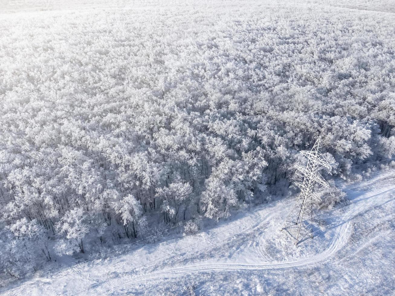 High-voltage power transmission tower in a frozen forest in winter. photo