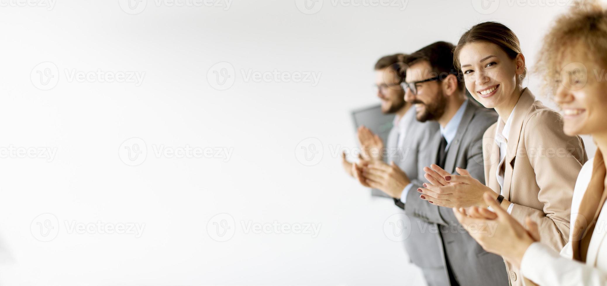 Group of diverse young coworkers standing in a row and applauding at office photo