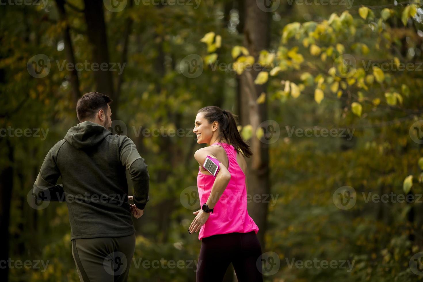 Athletic couple running together on the forest trail photo