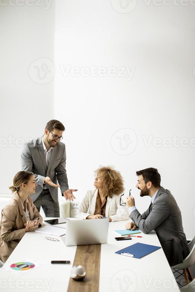 Group of young business people working and communicating while sitting at the office desk together photo