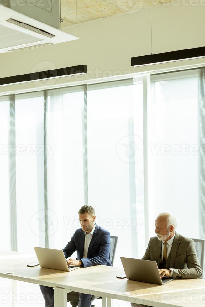 Businesspeople sitting and working in laptops at the office photo