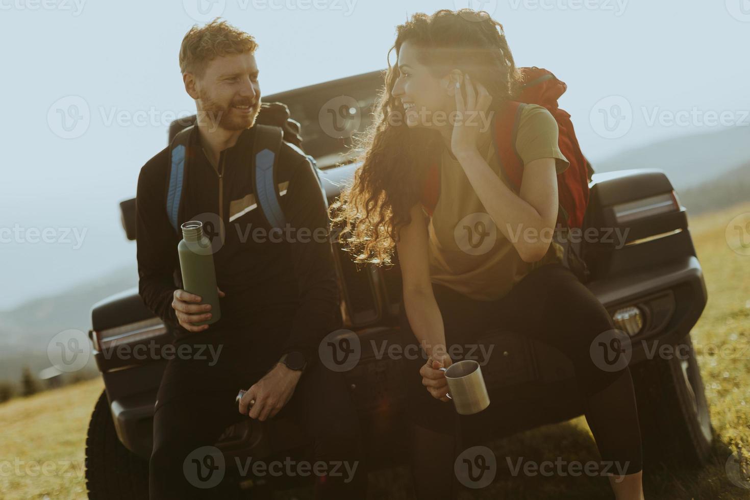 Young couple relaxing on a terrain vehicle hood at countryside photo