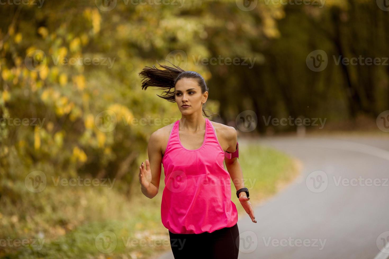 Young fitness woman running at forest trail photo