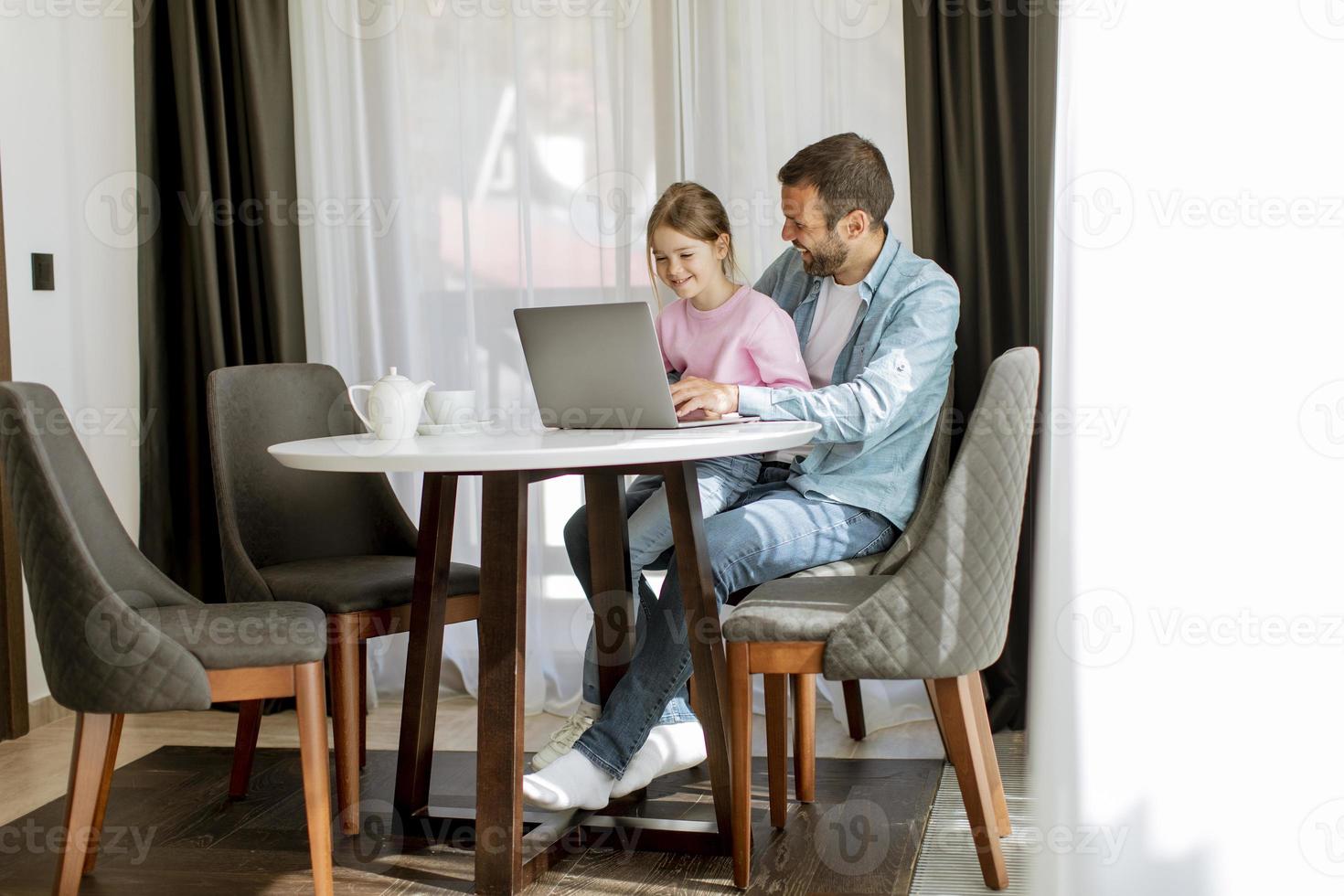 Father and daughter using laptop computer together photo