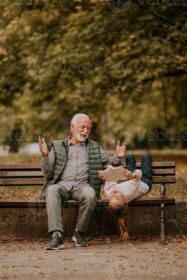 abuelo pasando tiempo con su nieta en un banco en el parque el día de otoño foto