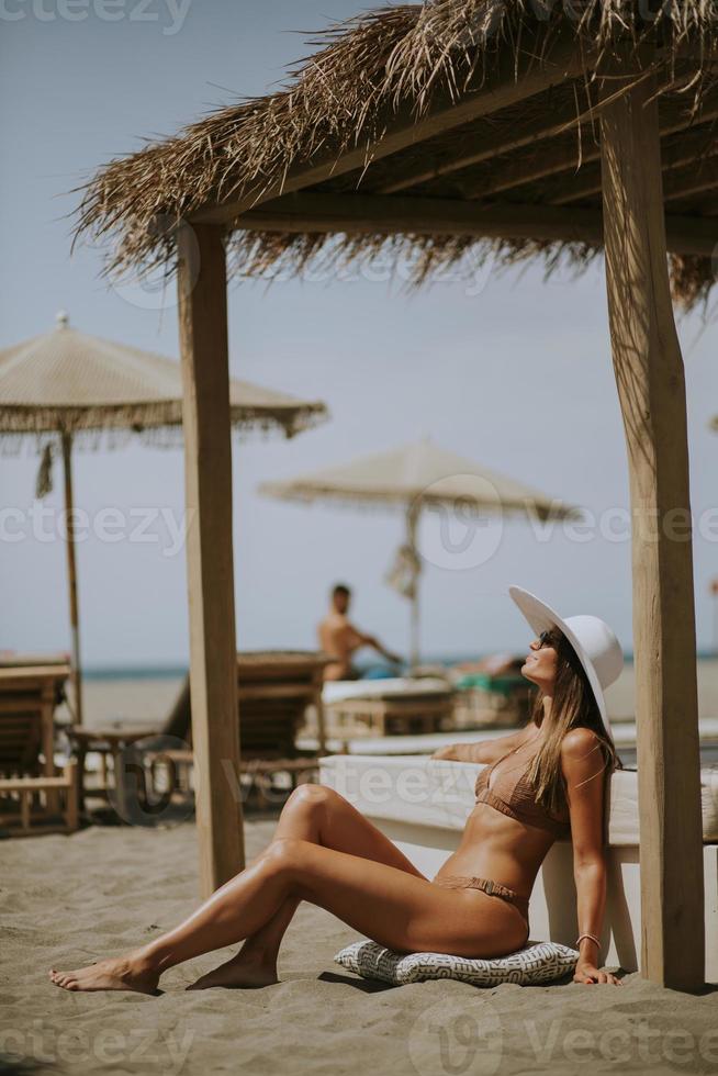 Young woman in bikini sitting on the beach at summer day photo