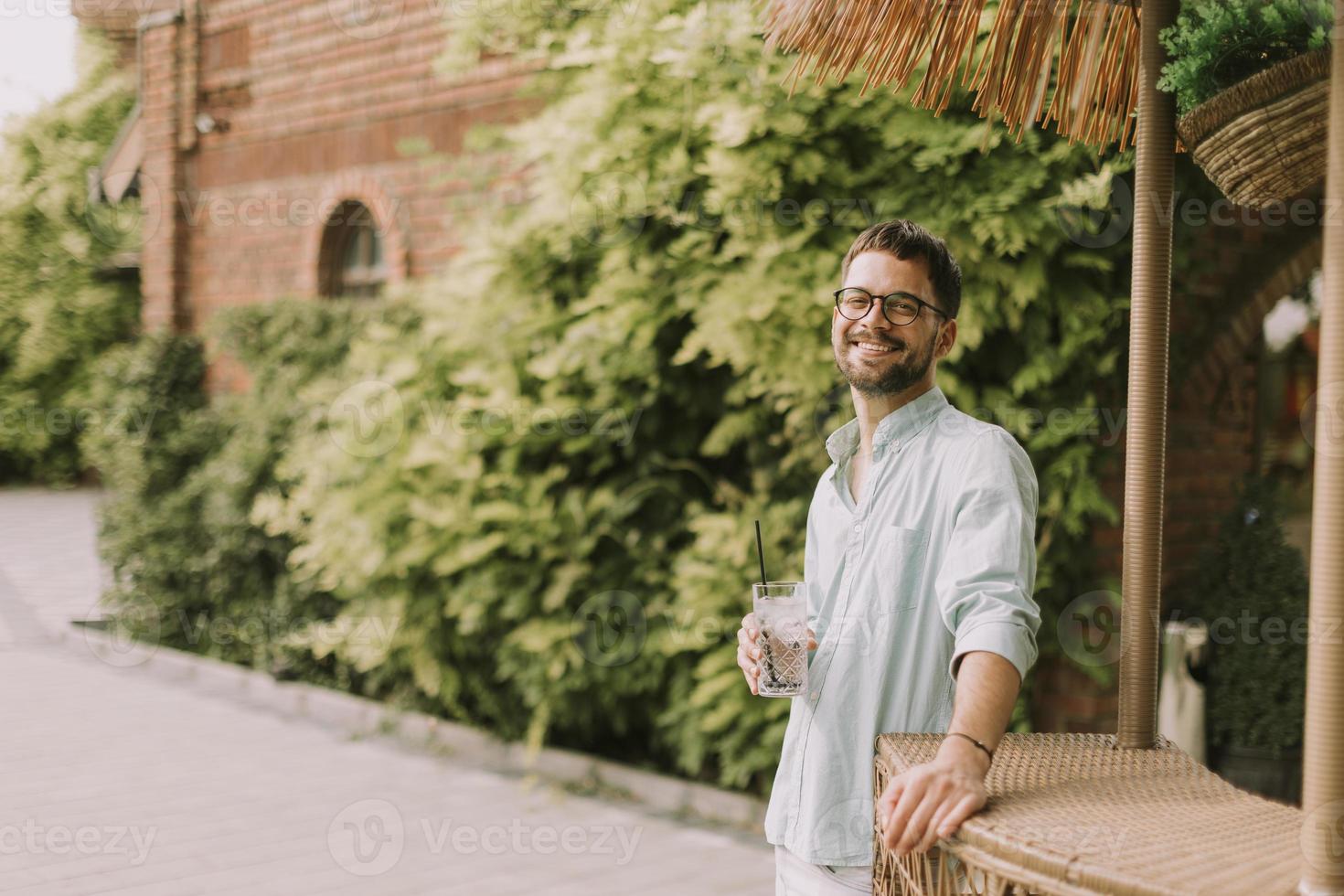 Young man drinking fresh cold lemonade at the pool bar photo