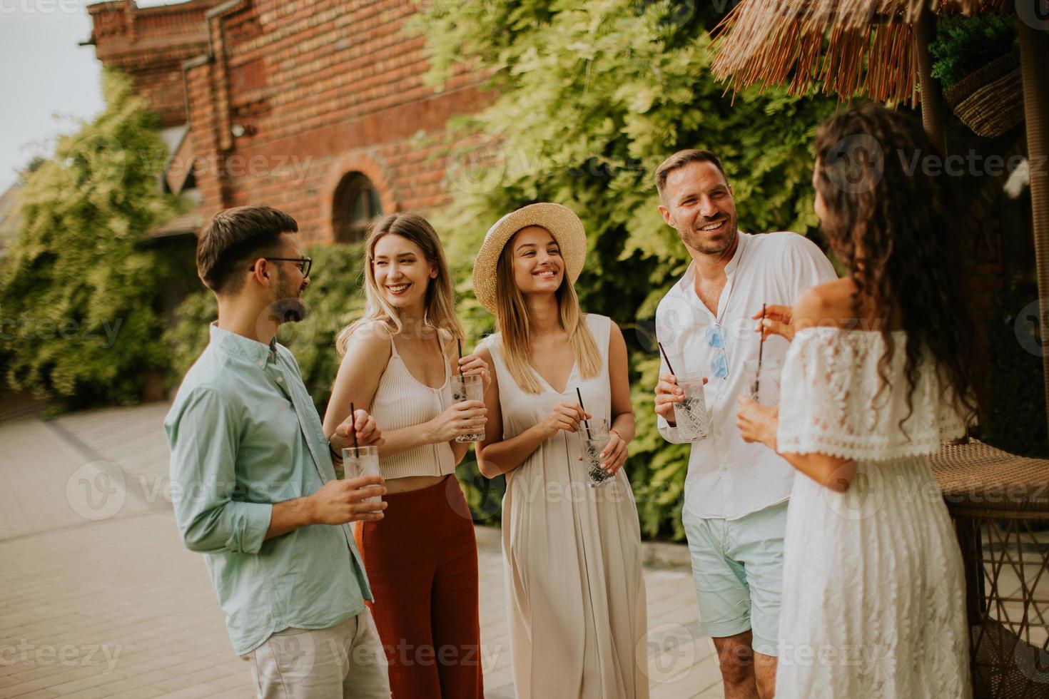 Group of young people cheering and having fun outdoors with drinks photo