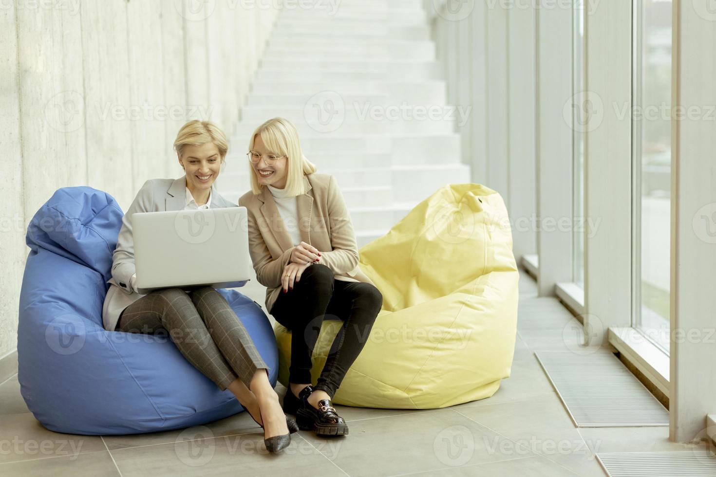 mujeres de negocios que usan computadoras portátiles en bolsas perezosas en la oficina moderna foto