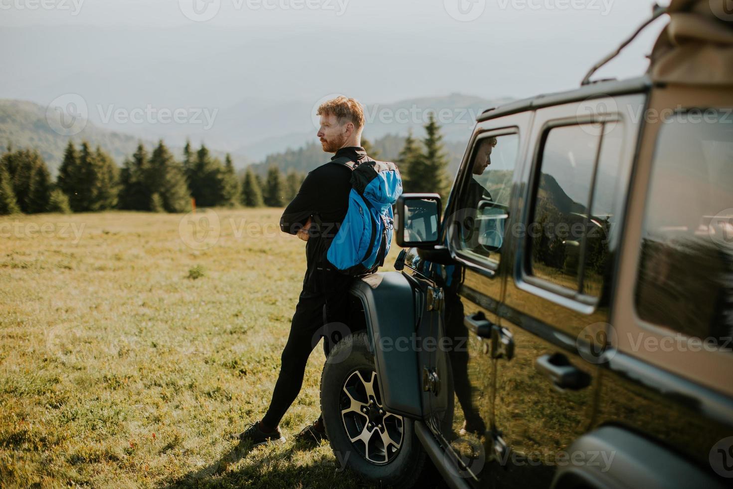 Young man relaxing by the terrain vehicle hood at countryside photo