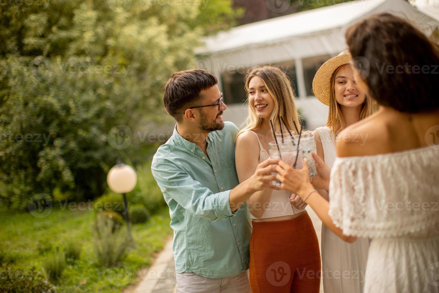 grupo de jóvenes felices animando con limonada fresca en el jardín foto