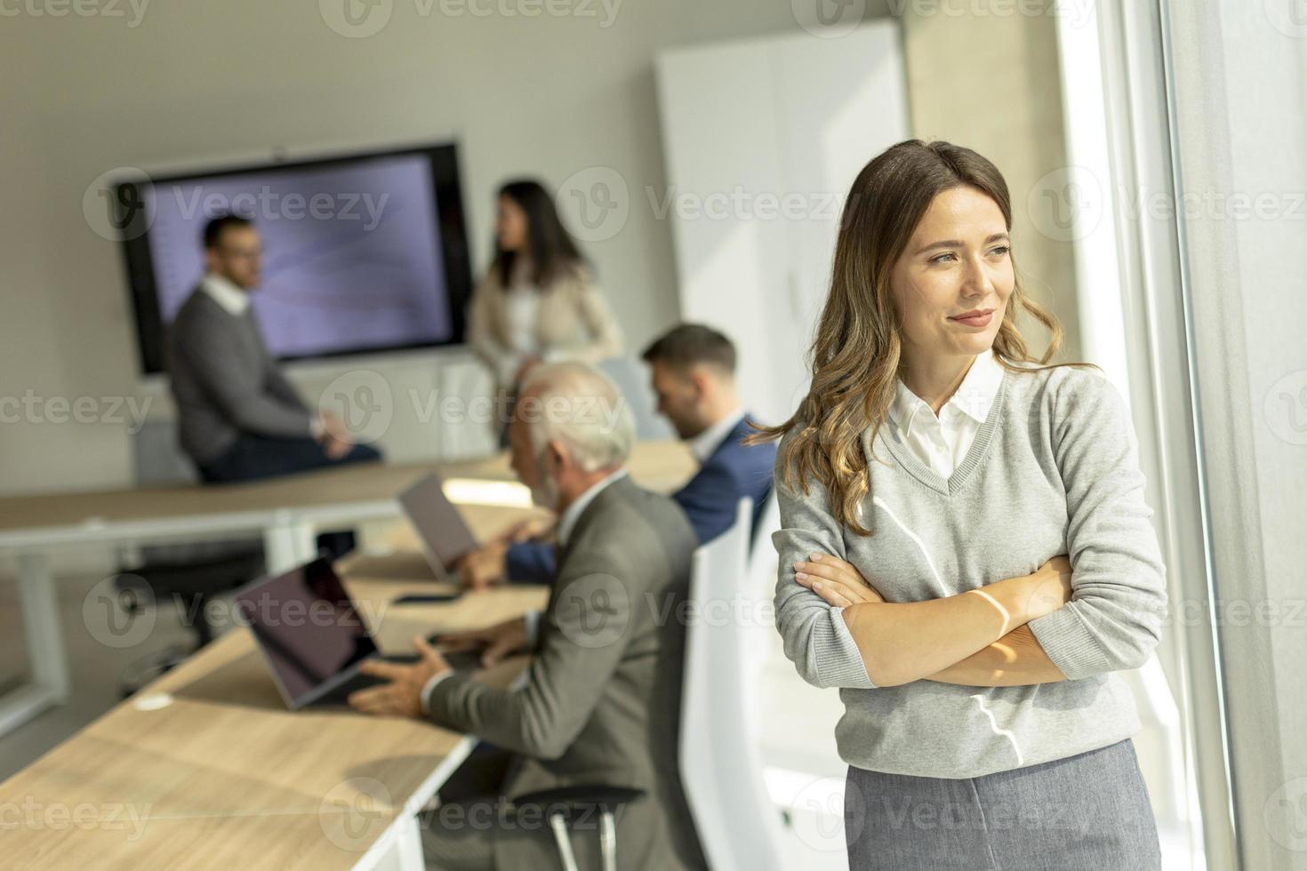 joven mujer de negocios en la oficina de inicio con los brazos cruzados frente a sus colegas como líder del equipo foto