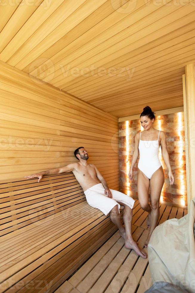 Young couple relaxing in the sauna and watching winter forest through the window photo