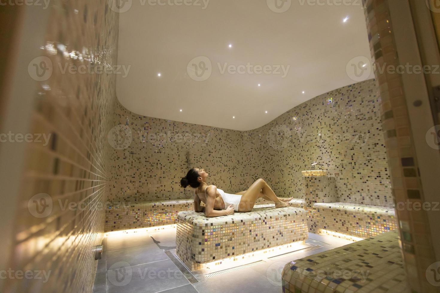 Young woman relaxing on the tepidarium bed in the spa photo