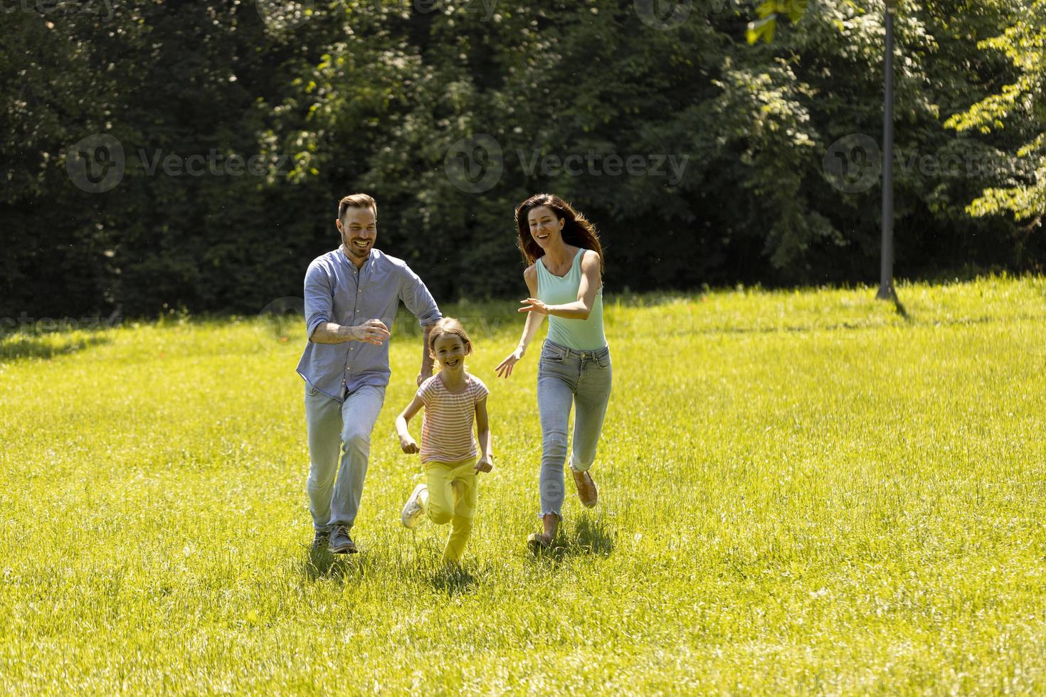 Happy young family with cute little daughter running in the park on a sunny day photo