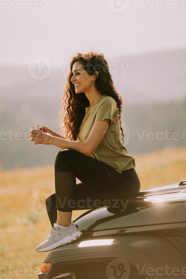 Young woman relaxing on a terrain vehicle hood at countryside photo