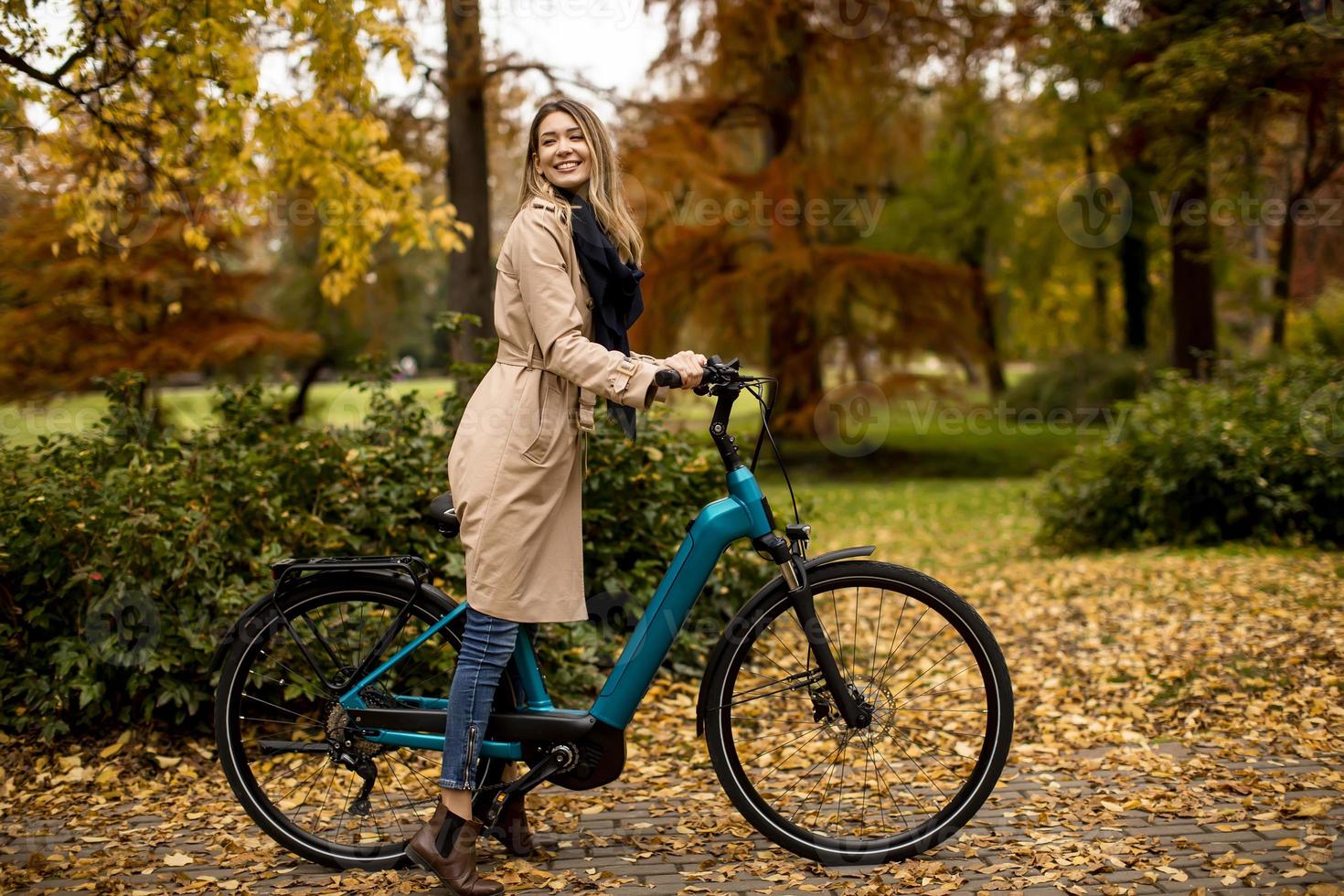 Young woman with electric bicycle in te autumn park photo