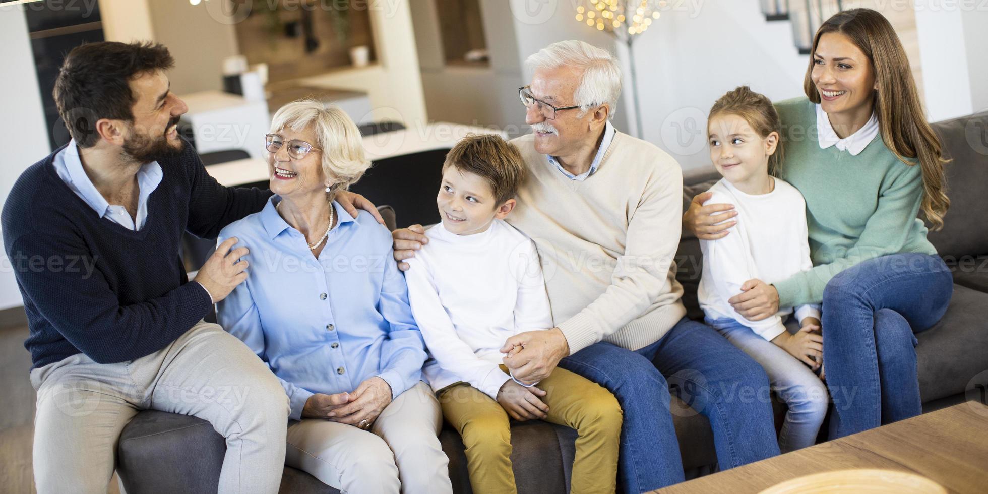 Multi generation family sitting together on the sofa at home and watching TV photo