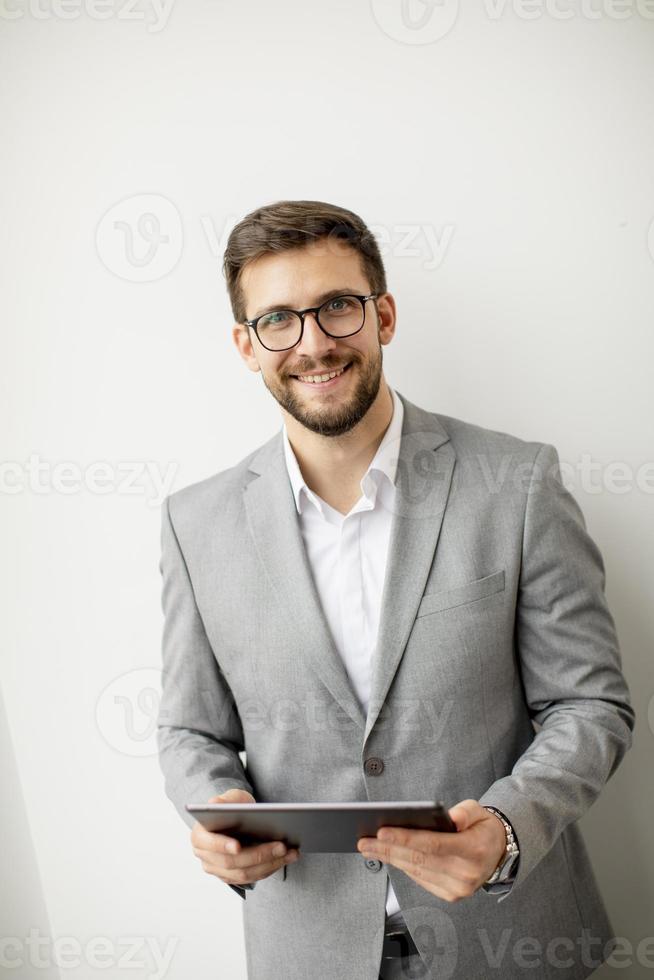 joven hombre de negocios moderno que usa tableta digital junto a la pared en la oficina foto