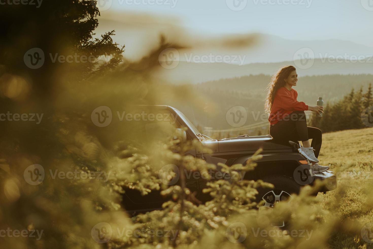 Young woman relaxing on a terrain vehicle hood at countryside photo