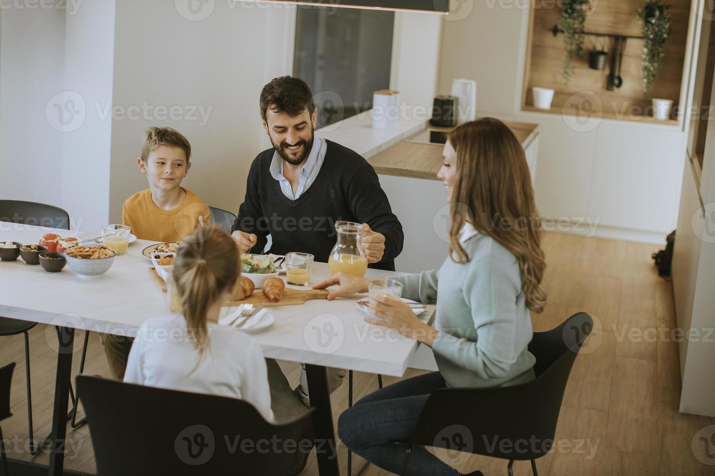 joven familia feliz hablando mientras desayuna en la mesa del comedor foto