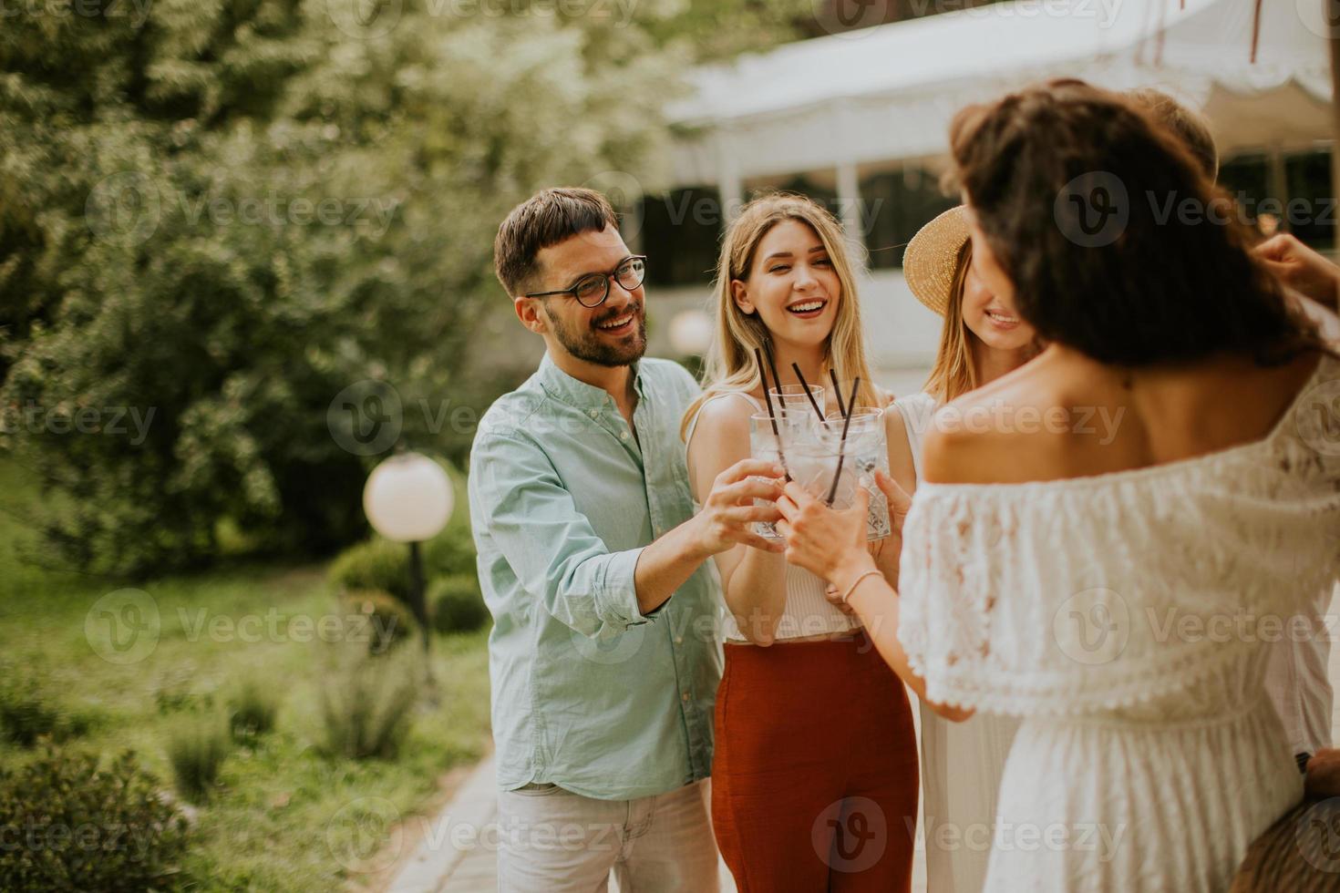 grupo de jóvenes felices animando con limonada fresca en el jardín foto