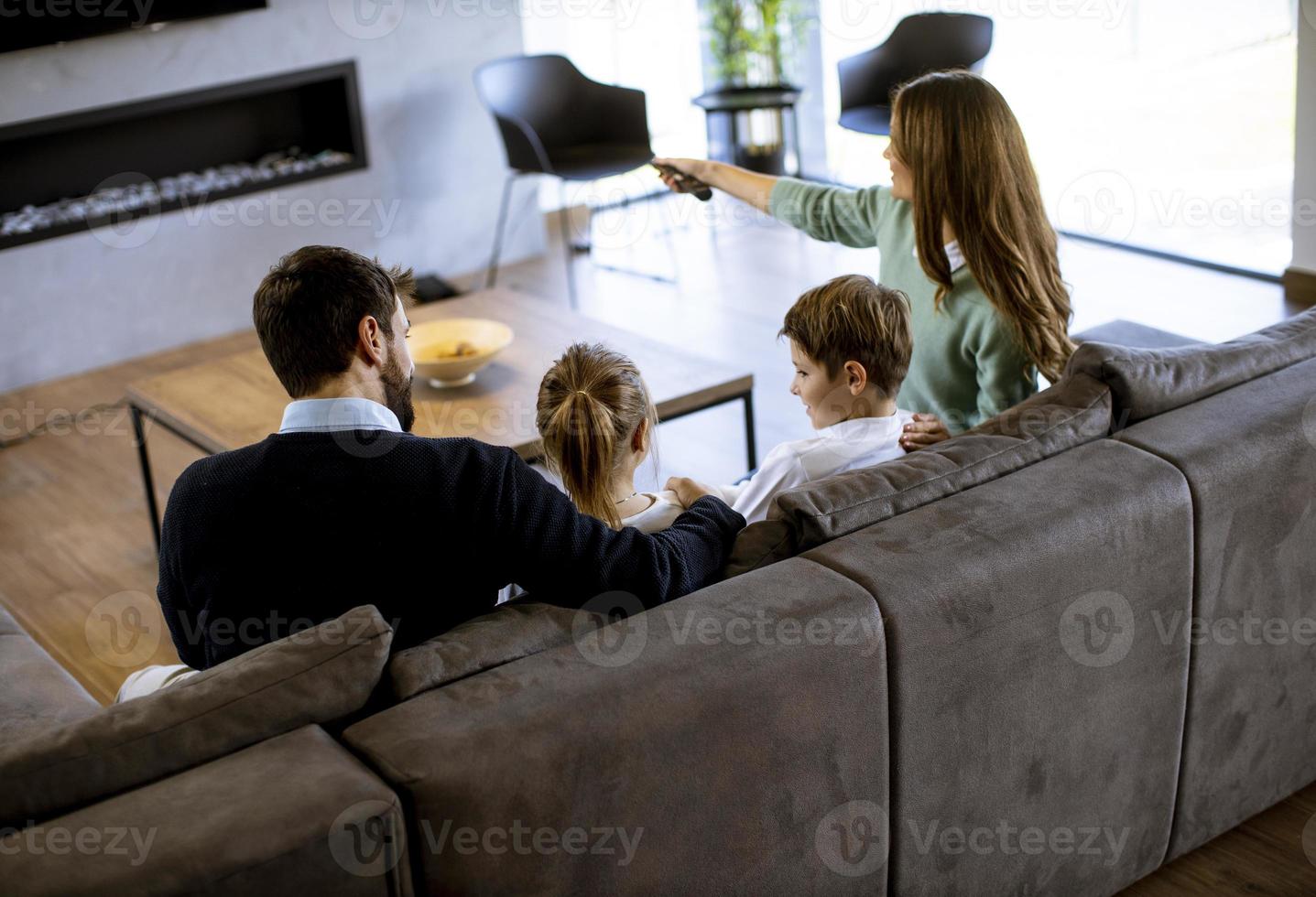 Young family watching TV together on the sofa in the living room photo