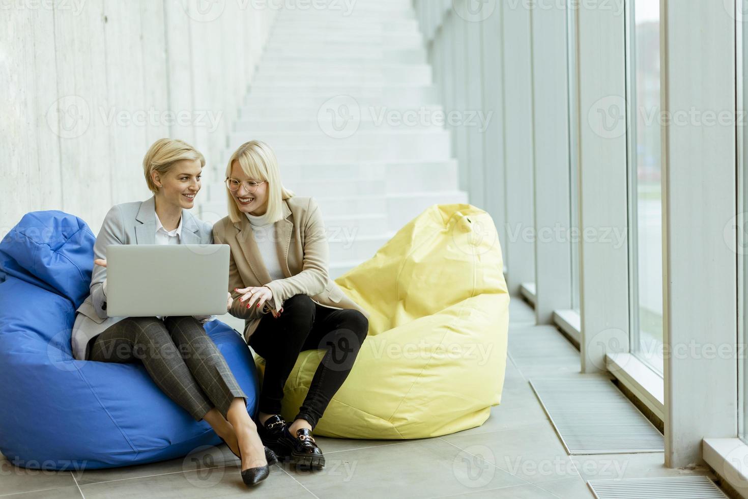 mujeres de negocios que usan computadoras portátiles en bolsas perezosas en la oficina moderna foto