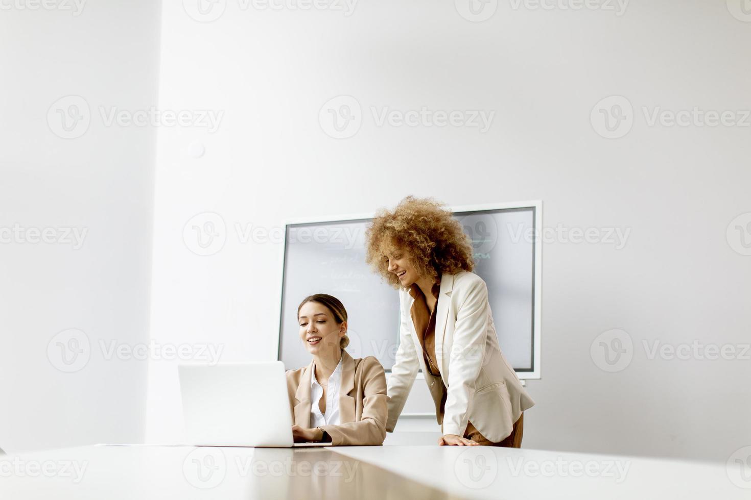 Young businesswomen discussing and using laptop in the modern office photo