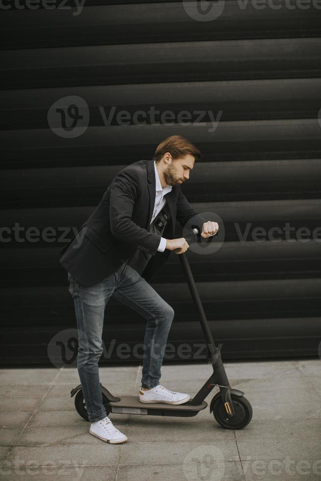 Joven empresario mediante teléfono móvil en scooter eléctrico foto