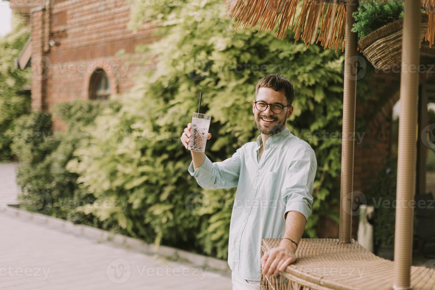 Young man drinking fresh cold lemonade at the pool bar photo