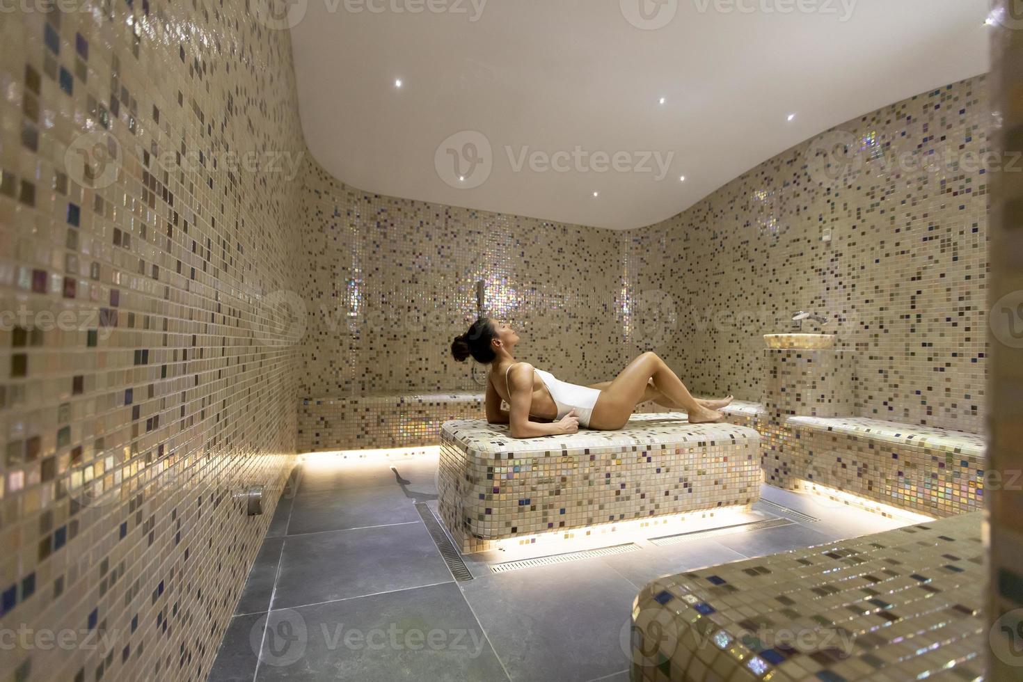 mujer joven relajándose en la cama tepidarium en el spa foto