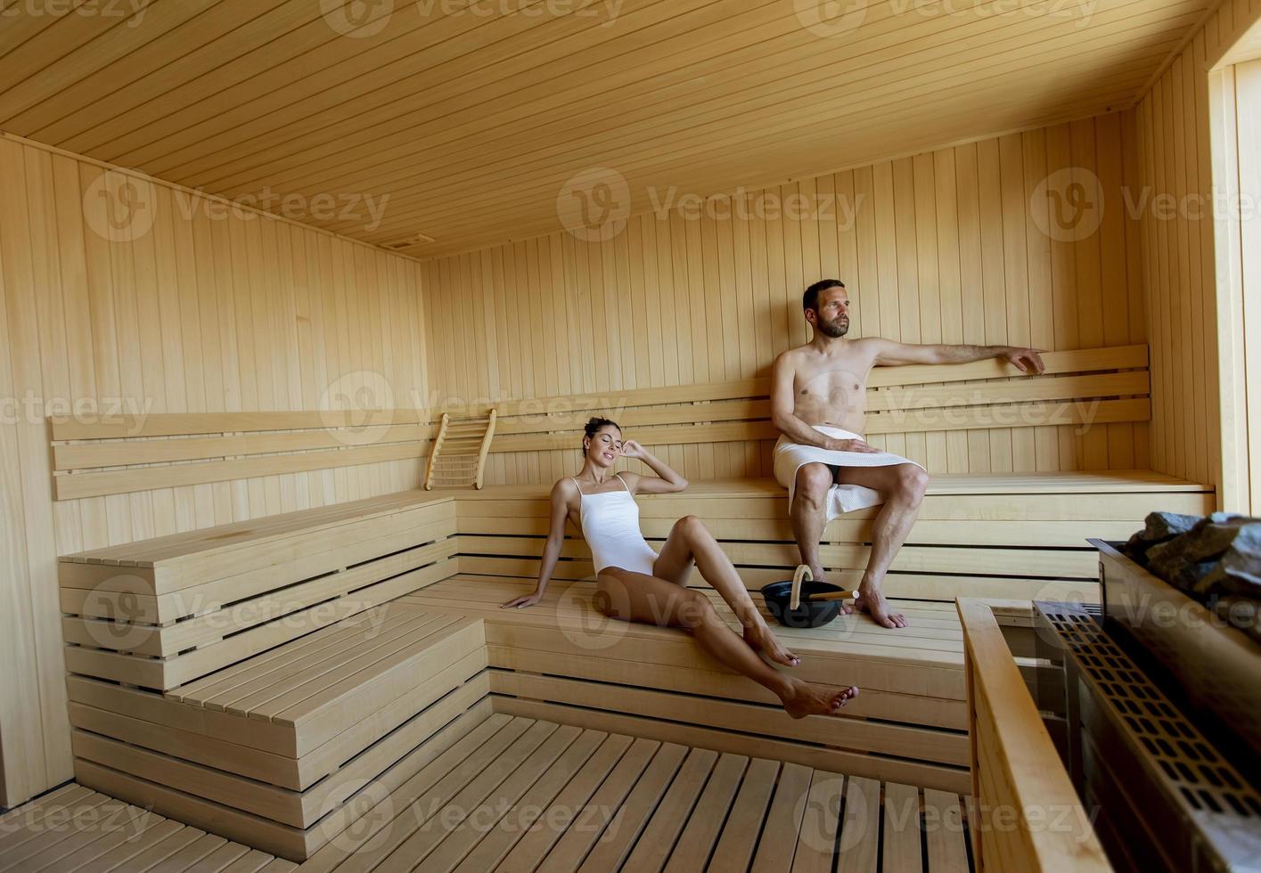 Young couple relaxing in the sauna and watching winter forest through the window photo