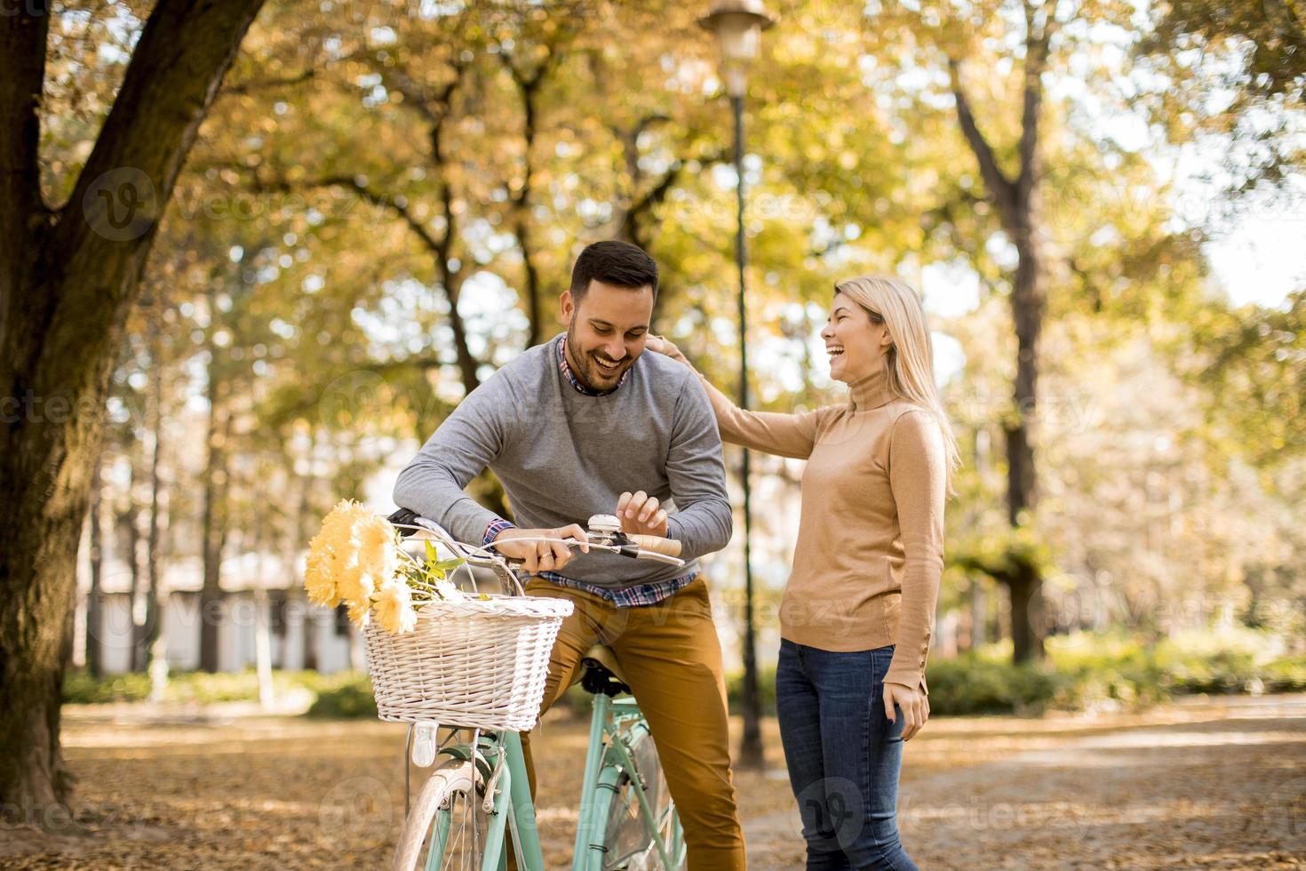 Active senior couple together enjoying romantic walk with bicycle in golden autumn park photo