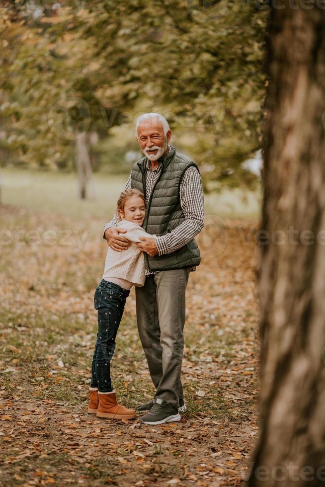 Grandfather spending time with his granddaughter in park on autumn day photo