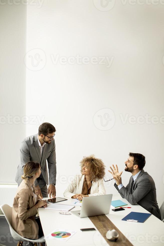 Group of young business people working and communicating while sitting at the office desk together photo