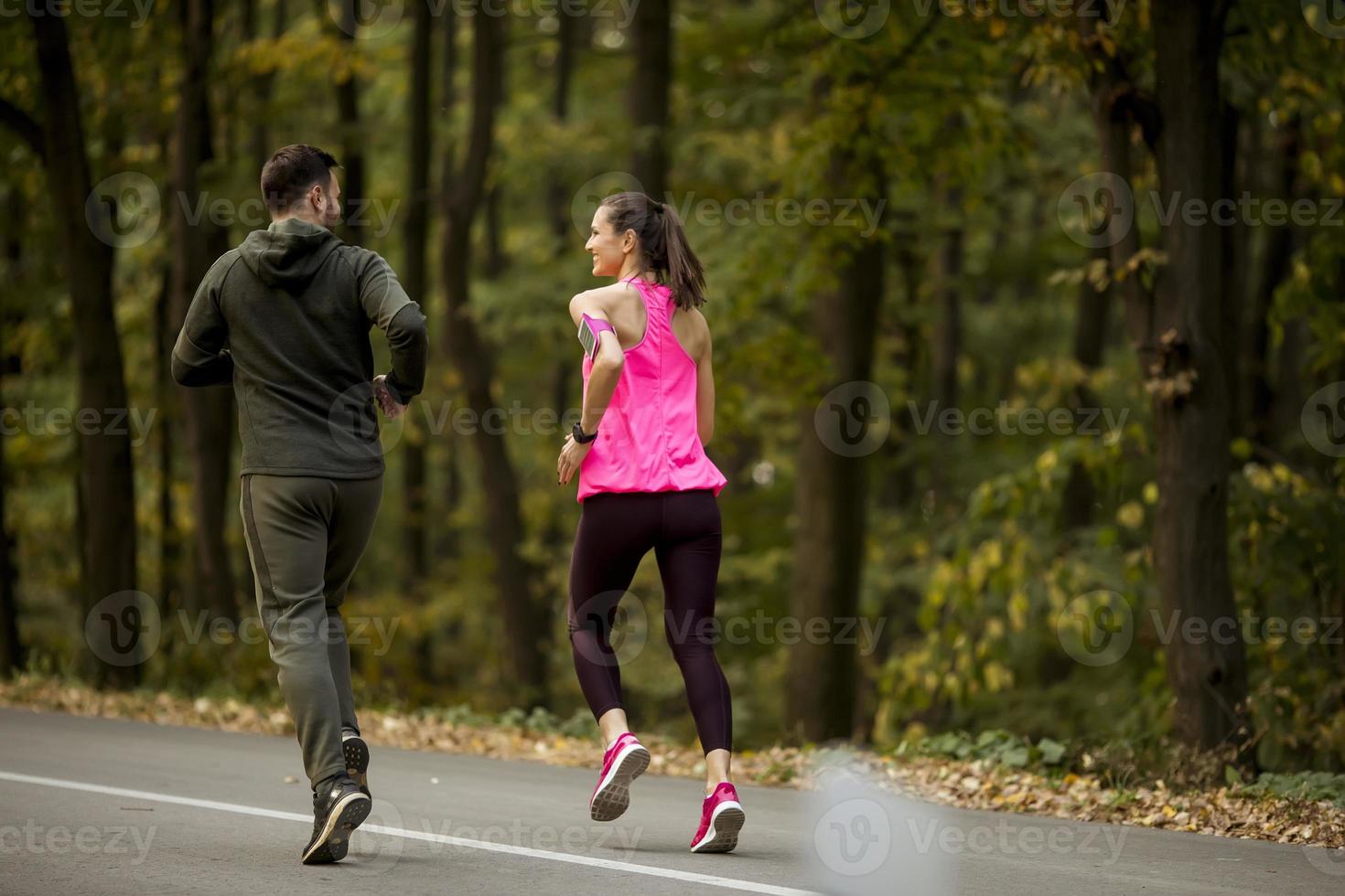 Athletic couple running together on the forest trail photo