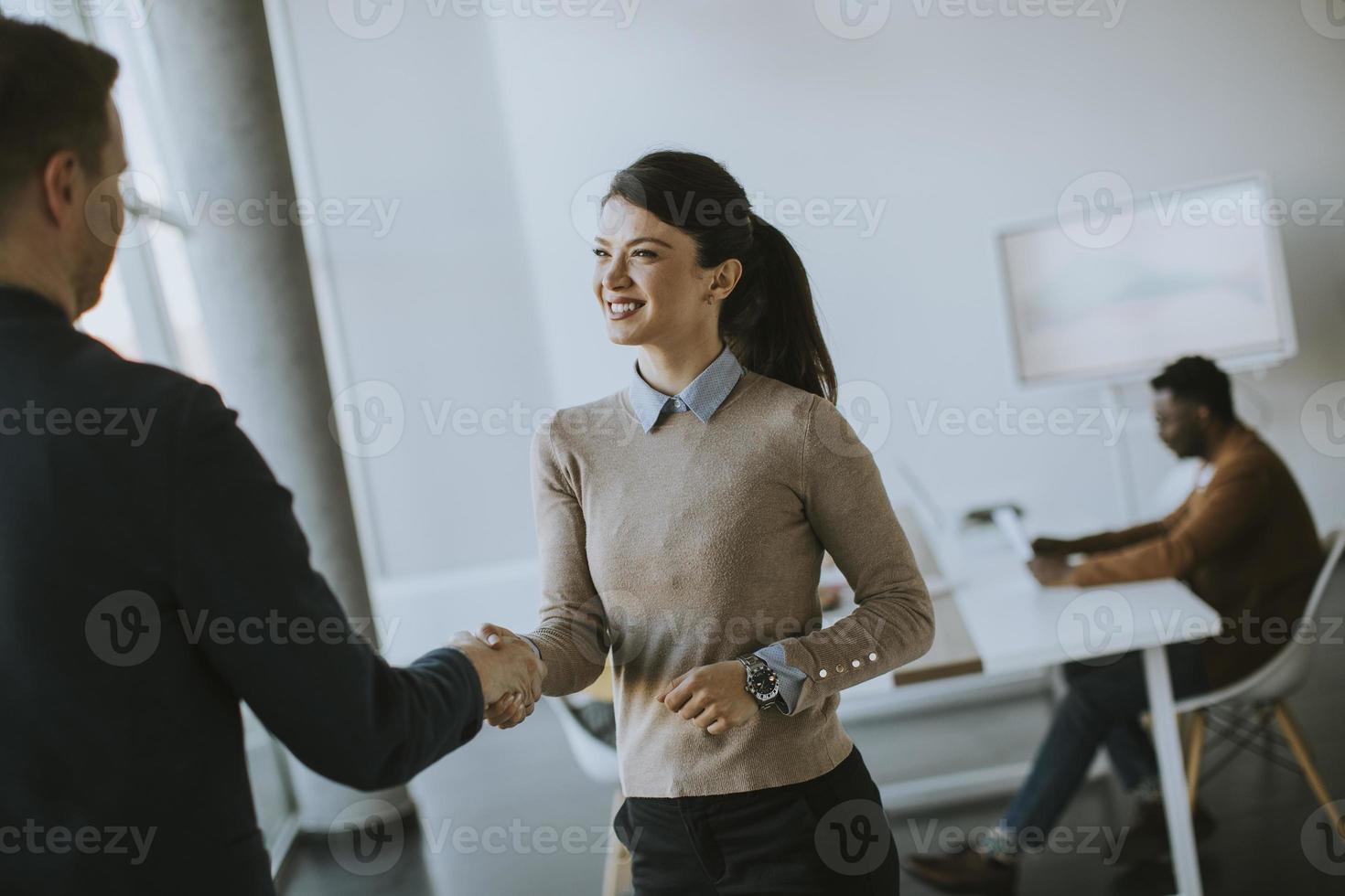 Young business partners making handshake in an office photo
