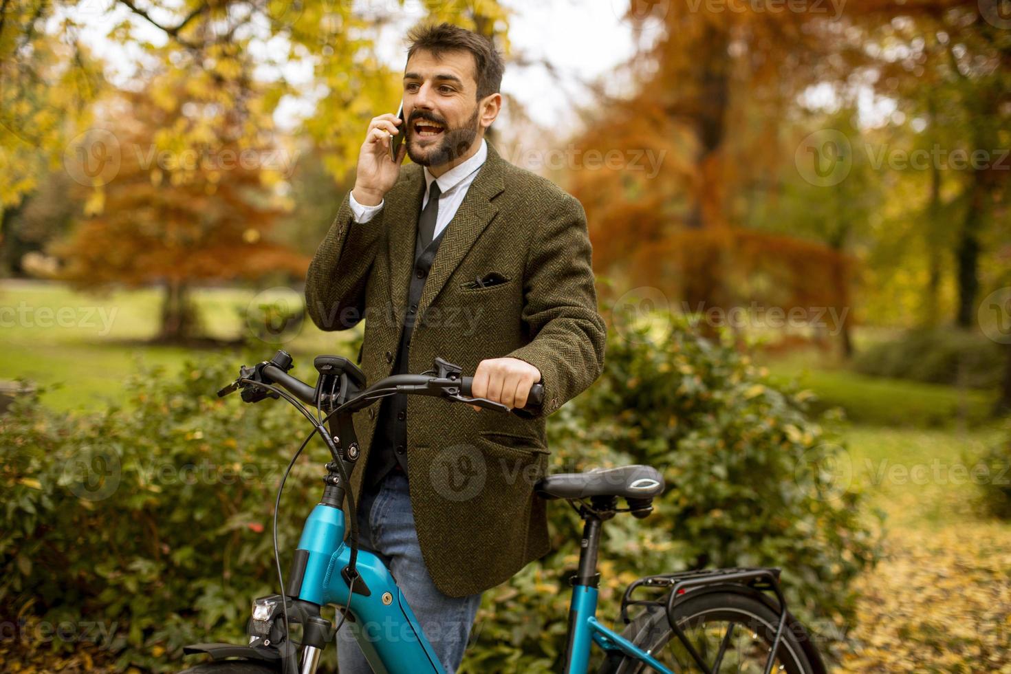 Young man with electric bicycle in the autumn park photo