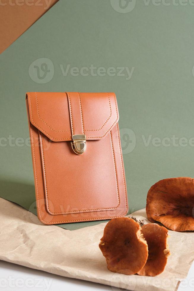 small brown bag and poisonous toadstools on a green background, eco-leather from mushroom mycelium photo