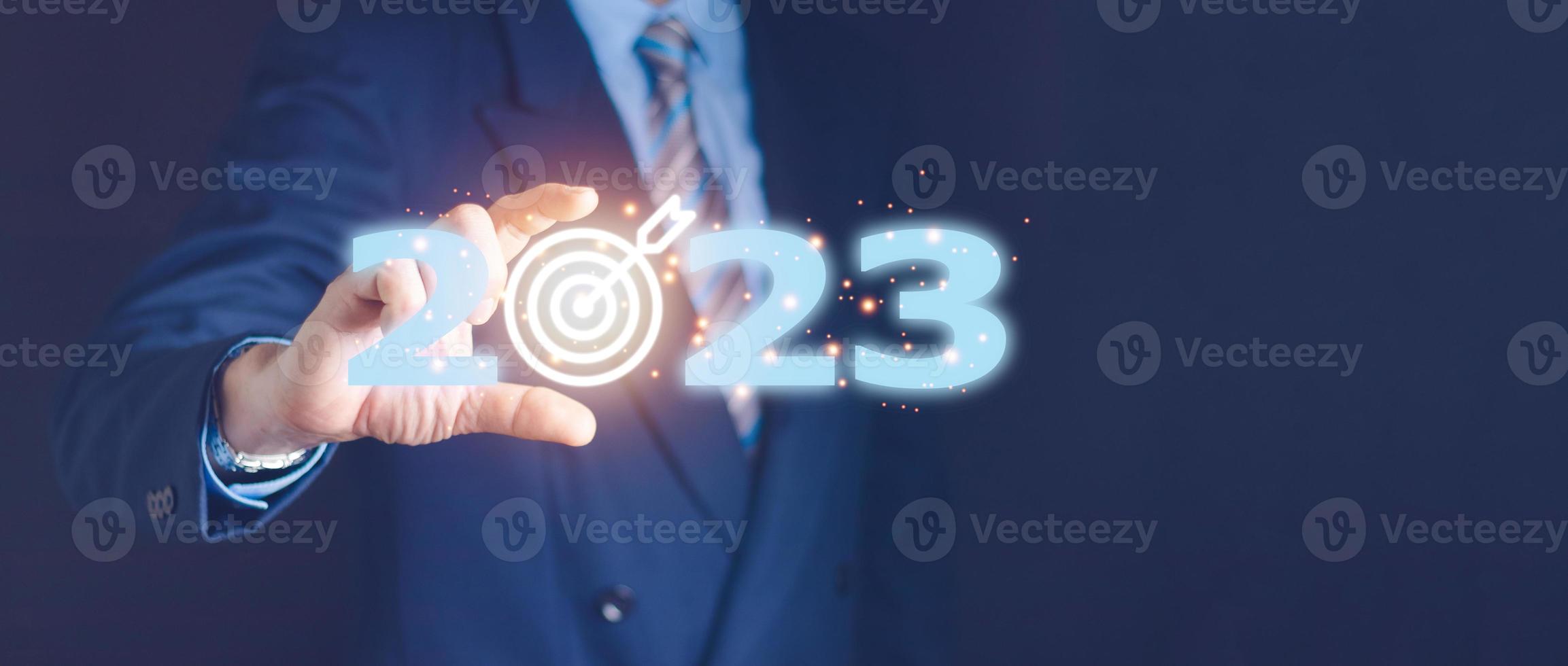 Businessman pressing 2023 start up business. Beginning of New Year 2023.Finger pressing blue start 2023 button on virtual interface on gray background with copy space for text. Concept of new year. photo