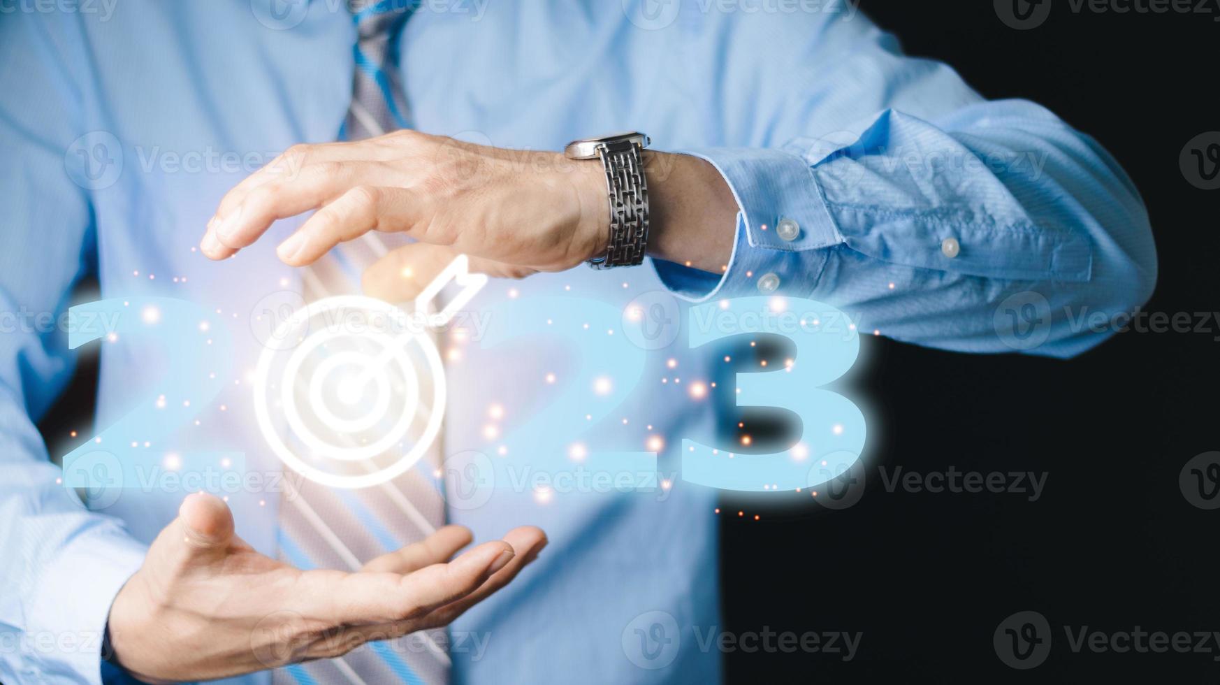 Businessman pressing 2023 start up business. Beginning of New Year 2023.Finger pressing blue start 2023 button on virtual interface on gray background with copy space for text. Concept of new year. photo