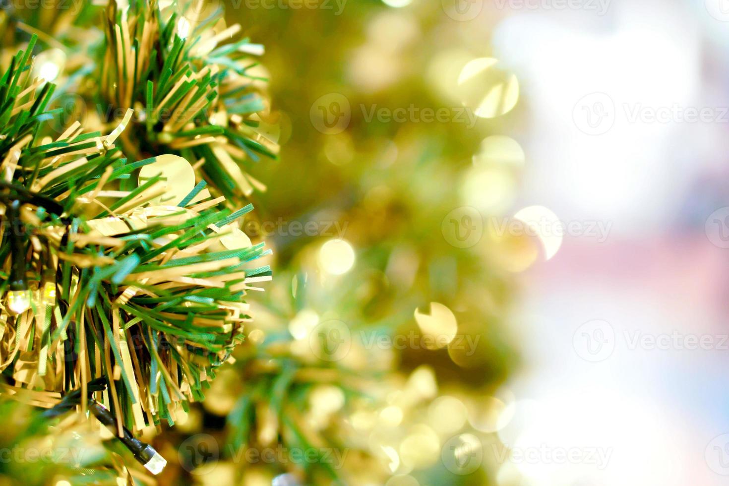 Closeup plastic pine leaves with bokeh of Christmas lighting and blurry of Christmas tree background. photo