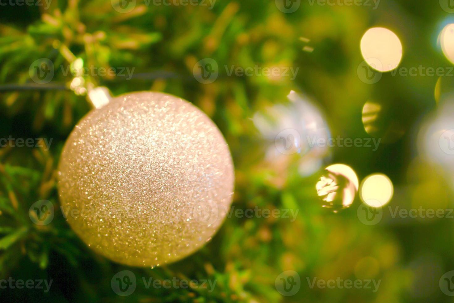 bolas de navidad doradas decoradas en pino el día de navidad con fondo de árbol de navidad borroso y bokeh de iluminación navideña. foto