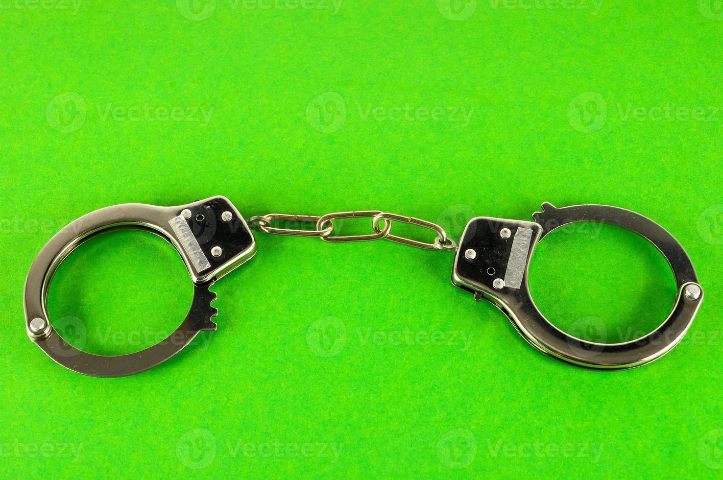 Metal handcuff on green background photo