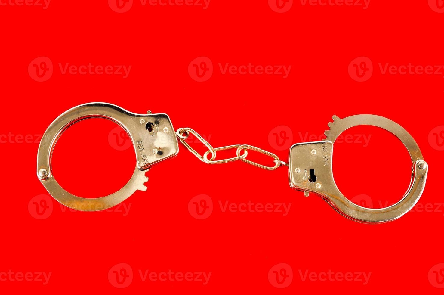 Metal handcuff on red background photo